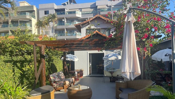 Un patio amueblado con muebles de mimbre, sombrillas y plantas en macetas.