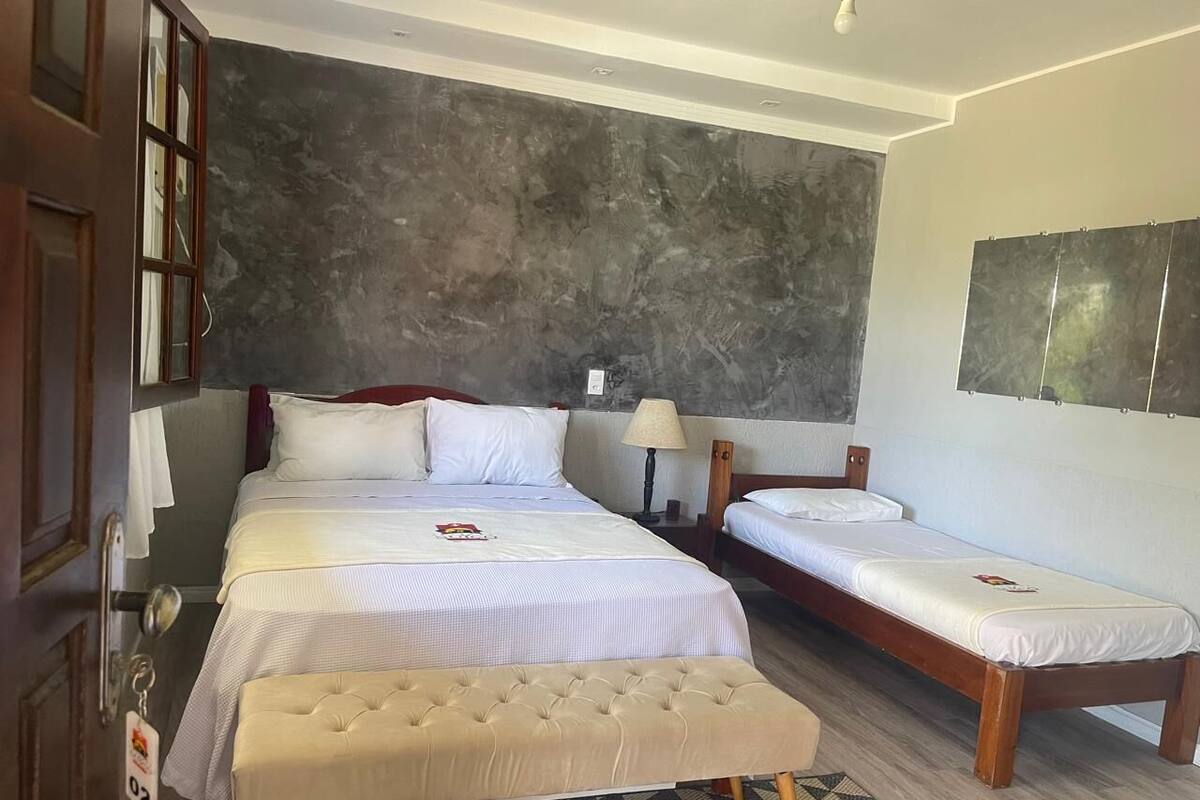 A hotel room with two beds, a large window, and a dark textured wall.