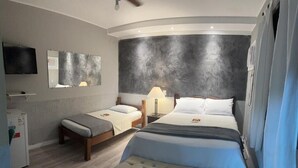 Una habitación de hotel moderna con una cama grande, una cama más pequeña, un banco, un televisor de pantalla plana y un cuadro abstracto de gran tamaño en la pared.