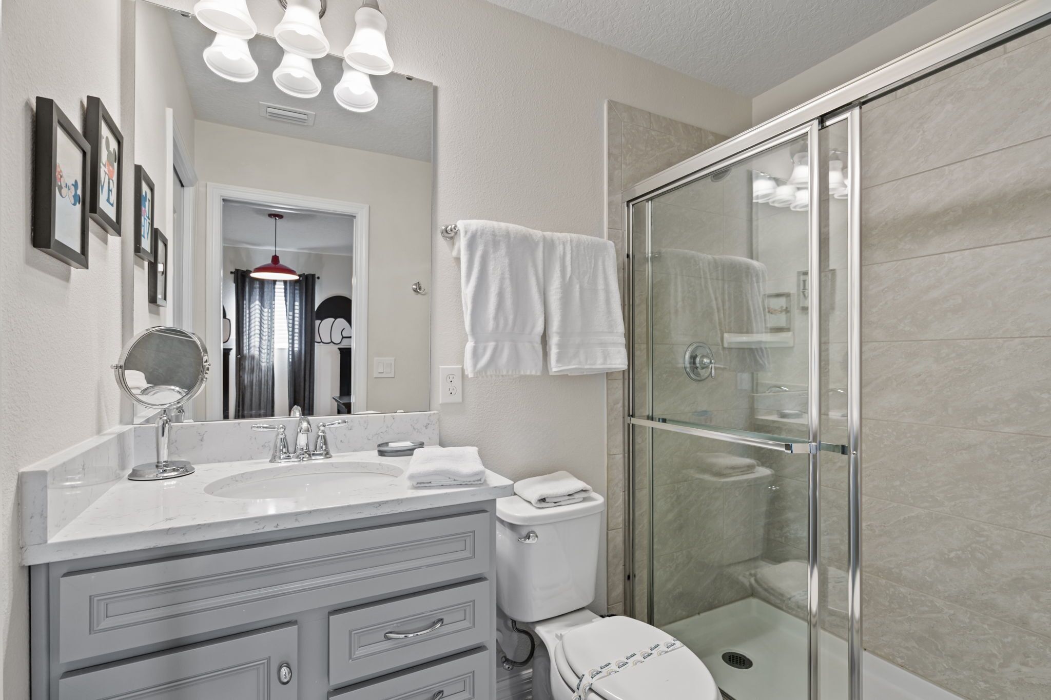 A modern bathroom with a glass shower enclosure, a white sink with a mirror, and a toilet.