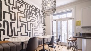 Una cocina moderna con un diseño geométrico en la pared, una mesa redonda para comer y taburetes de bar.
