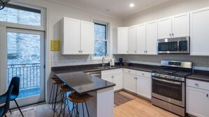 Una cocina moderna con armarios blancos, una estufa de acero inoxidable y un ventanal grande.