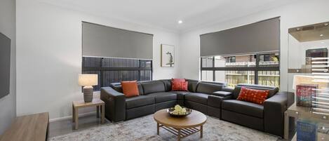 A modern living room with a sectional sofa, a coffee table, and a bookshelf.