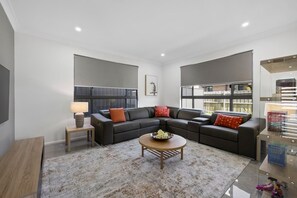 A modern living room with a sectional sofa, a coffee table, and a bookshelf.