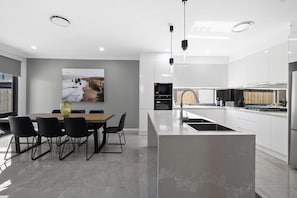 A modern kitchen with white cabinetry, a central island, and a dining area with a table and chairs.