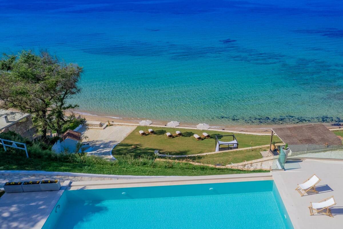 Une piscine avec des chaises longues et vue sur la mer.