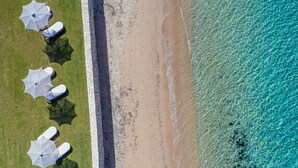 Vue aérienne d’une plage bordée d’une rangée de parasols et de chaises longues.