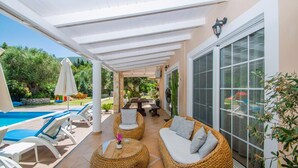 Un patio extérieur couvert, équipé de chaises longues, d’une table ronde et d’une piscine.