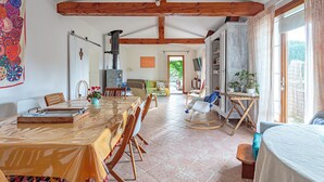 Un comedor amplio con una mesa y sillas de madera, una cocina con estufa, y vistas a un jardín a través de un ventanal.