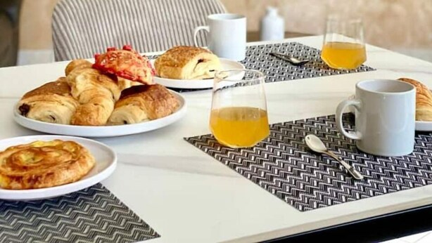 Een ontbijt met croissants, een glas sap en een tafel met een placemat.