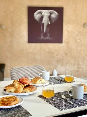 A breakfast setting with croissants, a glass of juice, and a table with a placemat. - Charming T3 Apartment in the Heart of Gap (Gap)