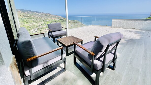 A balcony with two chairs and a table, overlooking a coastal landscape. - Mar a Vista by Your Madeira Rentals (Ponta do Sol)
