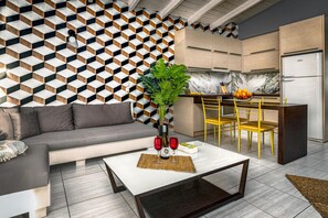 A modern living room with a gray sofa, a coffee table with red wine glasses, and a geometric patterned wall. - Marayas Modern Loft! (Zakynthos)