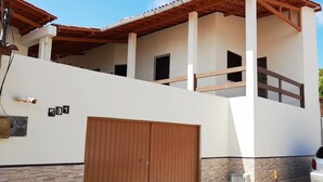Una casa moderna de dos pisos con balcón de madera, puerta de garaje y fachada de piedra.