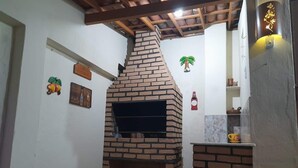 Cocina de ladrillo con horno empotrado, techo de madera y decoración mural que incluye frutas y una palmera.