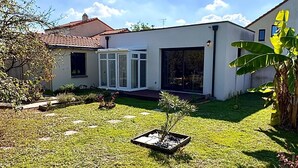 Et moderne hus med et solrum, en velplejet græsplæne og en lille have.