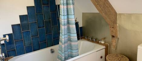 A bathroom with a bathtub, a shower curtain, a sink, and a toilet.