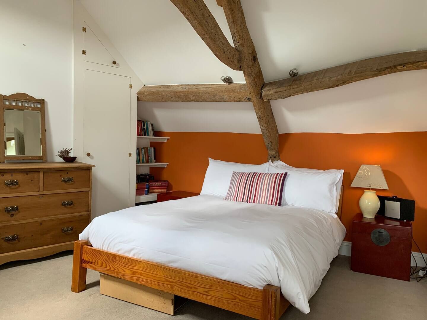 Une chambre à coucher avec un lit en bois, une commode, une table de chevet et une bibliothèque.