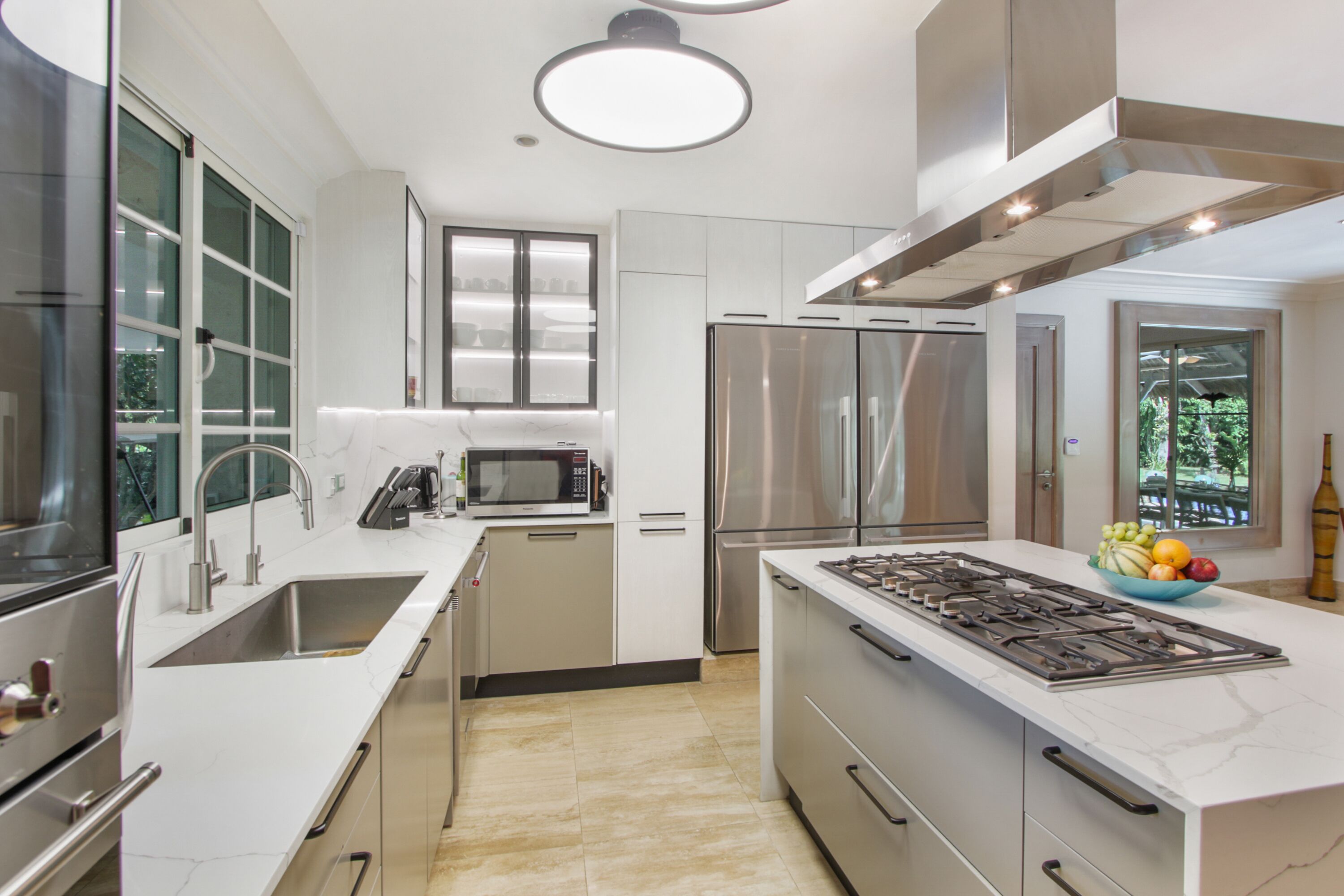 A modern kitchen with stainless steel appliances, white cabinetry, and a central island.