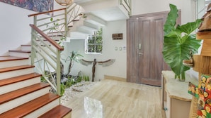 A staircase with wooden steps and a metal railing, a large green plant, and a wooden door in a well-lit room with a tiled floor. - 5BR Villa with Pool&Beach in Punta Cana (Punta Cana)