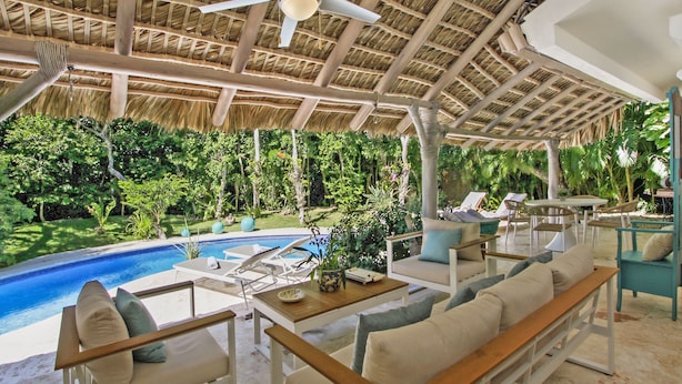 A poolside area with lounge chairs, a wooden table, and a ceiling fan. - 5BR Villa with Pool&Beach in Punta Cana (Punta Cana)