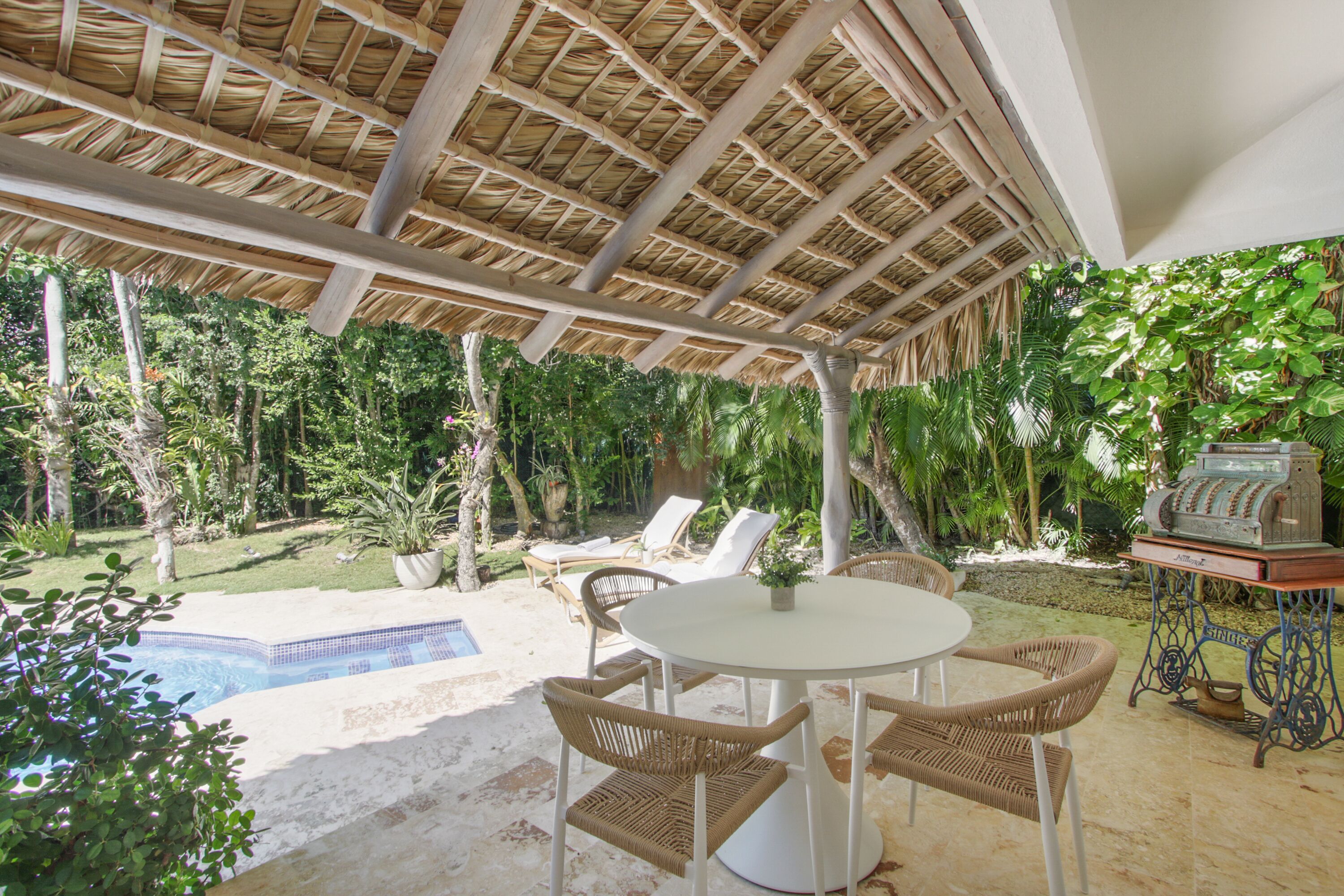 Un área de piscina con sillones, una mesa y una parrilla.