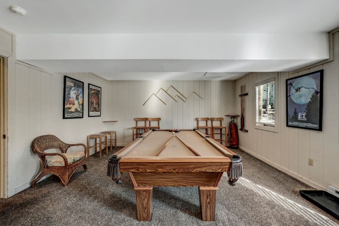 A pool table in a room with white walls, a ceiling fan, and framed posters.