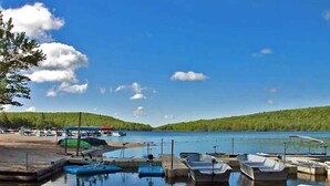 A marina with boats docked, a clear sky, and a forested hill in the background. - Walk 2 Ski: Groups, Kids, Spacious & Well-Stocked (Lake Harmony)