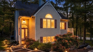 A house with a porch, a well-lit entrance, and a garden with pathways. - Walk 2 Ski: Groups, Kids, Spacious & Well-Stocked (Lake Harmony)