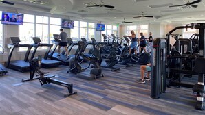 Ein Fitnessraum mit Laufbändern, Crosstrainern und Gewichten.