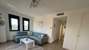 A living room with a sofa, a coffee table, a rug, and a wardrobe. - Apartamento en la Playa las Marinas en Denia (VC)