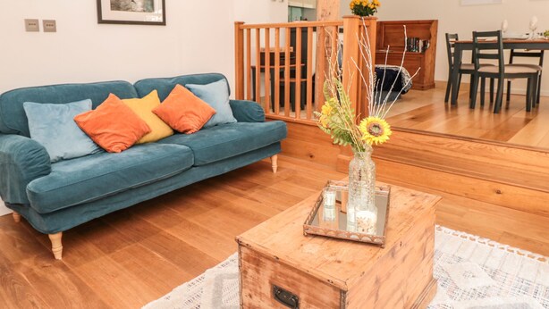 Un salon avec un canapé bleu, une table basse en bois et un vase rempli de fleurs.