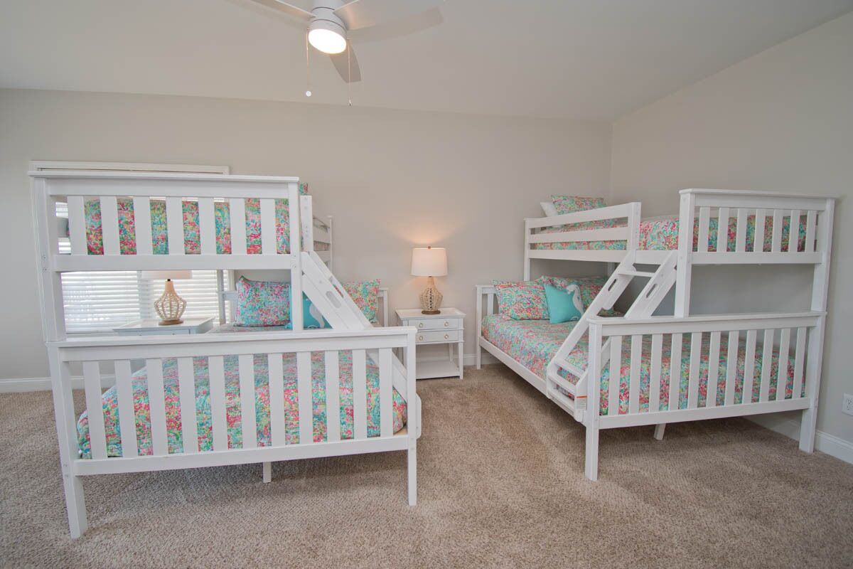 A bedroom with two bunk beds, a nightstand, a lamp, and a ceiling fan.