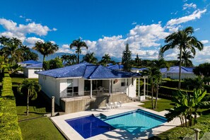 A resort with a swimming pool, white buildings with blue roofs, and palm trees. - Hotel Palma Verde (Armenia)