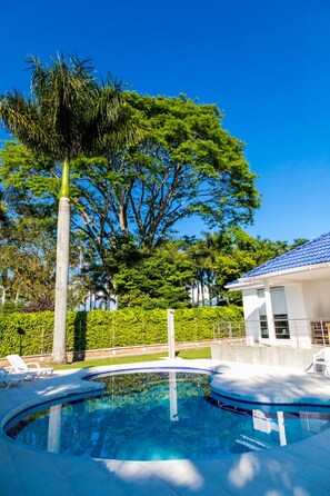 A swimming pool with a curved edge, surrounded by a well-maintained lawn and a tall palm tree. - Hotel Palma Verde (Armenia)
