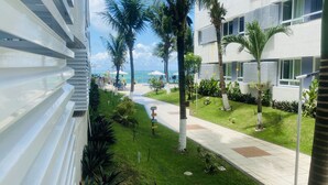 Ein Hotelinnenhof mit einem Weg, Palmen und Blick aufs Meer.