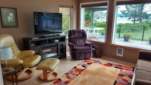 Una sala de estar con televisor, sillón de cuero y un banco acolchado.