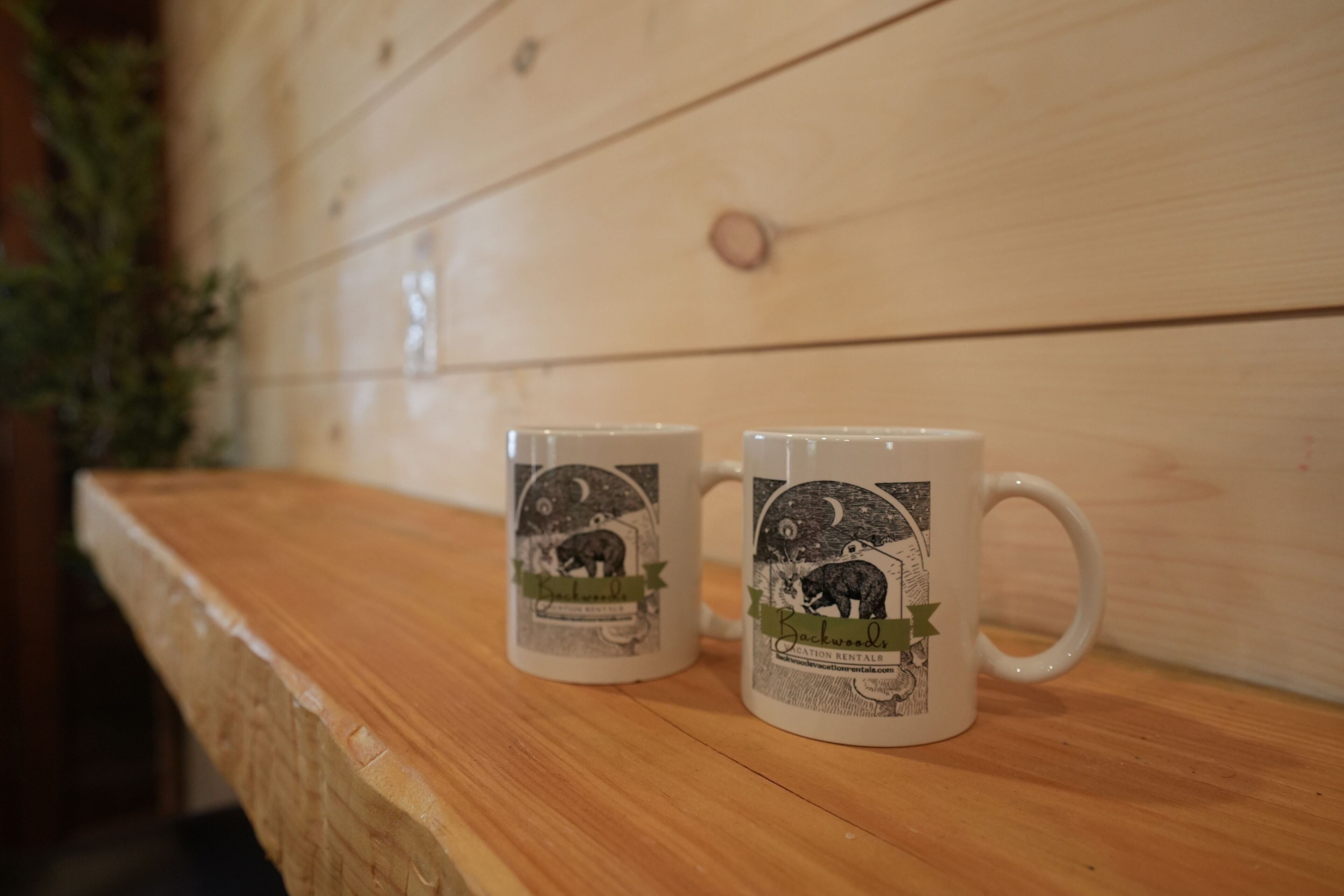 Deux tasses blanches ornées de motifs animaliers, posées sur une surface en bois.