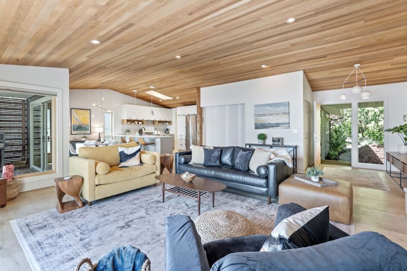 A modern living room with a wooden ceiling, a sofa set, a coffee table, and a rug.