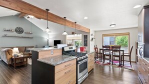 Una cocina moderna con encimeras de granito, una isla central, armarios de madera e iluminación colgante.