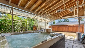 Un jacuzzi bajo una pérgola de madera con vista a un patio trasero.