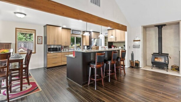 Una cocina amplia con gabinetes de madera, una isla central con taburetes de bar, estufa integrada y un ventanal grande.
