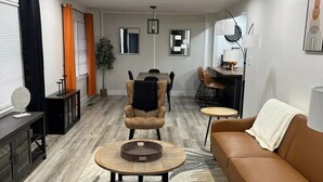 Una sala moderna con sofá, sillón, mesa de centro y comedor.