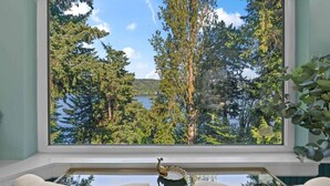 A room with a large window overlooking a forest and a lake.