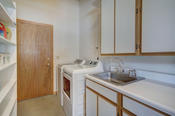 A compact kitchen with a built-in oven, a sink, and a wooden door.