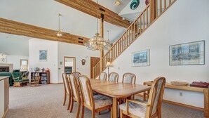 Un vaste espace dédié à la salle à manger, avec une table et des chaises en bois, un escalier et une vue sur le salon.