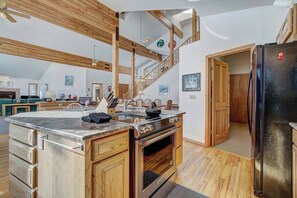 A spacious kitchen with wooden beams, a large island, and a modern stove.