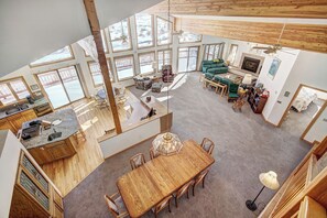 A spacious living area with a large wooden dining table, multiple seating options, and a fireplace.