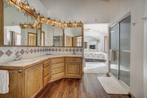 Un bagno con un mobile lavabo in legno, uno specchio grande e un box doccia in vetro.