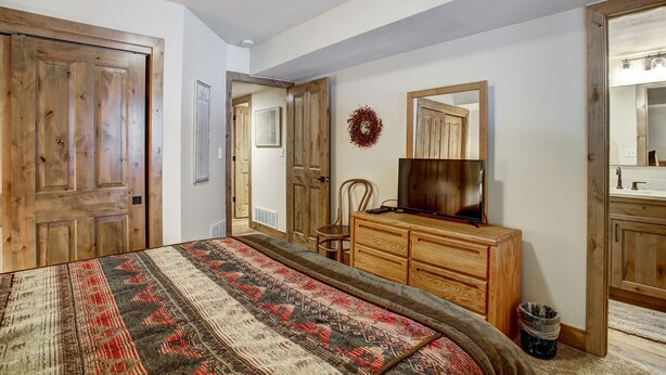Une chambre à coucher avec un lit en bois, une commode, un téléviseur et un miroir.